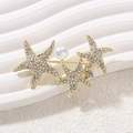Golden starfish brooch set with white crystals and a pearl on a white textured base - Starfish Style (YNCP7140)