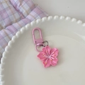 Detailansicht eines rosa Kirschblüten-Schlüsselanhängers aus Harz auf weißem Teller - Rosenrot