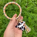 Détail du bracelet porte-clés en similicuir avec pendentif vache et frange à carreaux - Grille Colorée