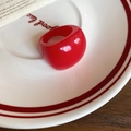 Primo piano di un anello geometrico in resina rossa su un piatto decorativo bianco - Rosso