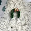 Detail eines grünen Weihnachtskranz-Tortensteckers mit roten und goldenen Schleifen-Akzenten - Kranz Stil D