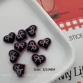 Macro shot of 8mm and 10mm black resin heart nail charms with pink bow accents - Black Purple