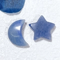 Macro detail of natural blue stone moon and star carvings on a white textured background - Star and Moon / Blue Aventurine
