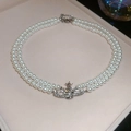 Detailed macro view of double-layer pearl necklace with a crystal-encrusted Saturn pendant - Double Layer Pearl Necklace / White