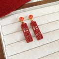 Detail der roten chinesischen Pferdeohrringe mit goldenen Glückssymbolen auf Samt - Glückliches Sternzeichen Pferd Reichtum Stil