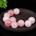 Perle tonde in quarzo rosa naturale lucido presentate su un vassoio scuro con decorazione - Quarzo rosa