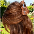 Guitar-shaped hair claw clip with brown marble pattern worn on long hair in a garden - Brown Marble Guitar / Yellow