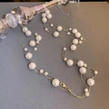 Elegant vintage pearl necklace with crystal beads and gold chain on a textured surface - Gold-White