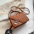 Brown quilted crossbody bag with gold chain strap and metallic lock on a beige backdrop - Caramel color