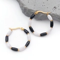 Vue détaillée des boucles d'oreilles créoles dorées avec perles émaillées bicolores - 31x31MM / Noir & Blanc