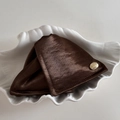 Detailansicht der braunen Satin-Haarklammer mit goldenem Metall-Label in Muschelschale - Braun