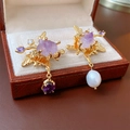 Detalle de pendientes asimétricos de oro con perla barroca, amatista y hojas de circón - Dorado