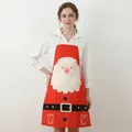 Festive red Christmas apron with Santa Claus print and neck strap worn by a person - Santa Claus