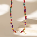 Detail of colorful beaded necklace featuring a white heart charm and a gold letter I pendant - Letter I