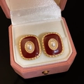 Detailed macro view of vintage gold-plated red enamel oval earrings with a pearl inlay - Vintage Palace Oval Pearl Style / Red