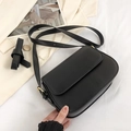 Retro black leather crossbody bag with gold hardware and adjustable strap on beige background - Black