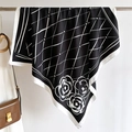 Detail of silk scarf with geometric grid and camellia flowers on a metal hanger - Black