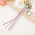 Close-up of heart-shaped keychain with silver metal pendant and colorful braided cord - Purple + Pink