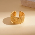 Macro view of golden adjustable open ring with dense granular texture and metallic finish - Gold
