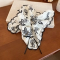 Detalle de un coletero de seda floral con bordes de encaje, lazo y perla elegante - Blanco