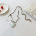 Collier chaîne argentée avec pendentif médaillon coeur poli sur fond esthétique épuré - Bandoulière chaîne