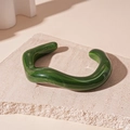 Detail of green marbled acrylic open bangle showing wave texture on a stone slab - Dark Green