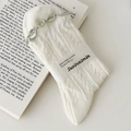 Creamy white cable knit crew socks with light green ruffle trim and paper packaging - Cream