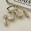 Detalle de pinza para el pelo dorada ondulada con textura de mármol perlado y estilo retro - Blanco Sirena