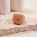 Close-up of minimalist apricot resin square ring on stone display with soft lighting - Brown
