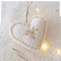 Dettaglio di ornamento a cuore in feltro di lana con bottone in legno e ricamo a mano - Cuore / Bianco