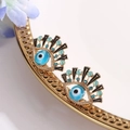 Elegant gold evil eye stud earrings with blue rhinestones on a decorative metal tray - KC Gold (6475)