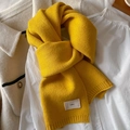 Detailed texture of bright yellow knitted scarf with 'emo' logo on beige coat - Ginger Yellow