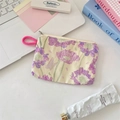 Floral fabric coin purse with pink handle shown on a desk with lifestyle accessories - Purple Floral