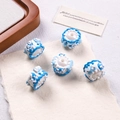 Macro shot of 5 hand-painted blue and white wave pattern acrylic beads for DIY crafts - White + Blue/White Cream + White Heart