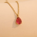 Elegant gold necklace with a red teardrop-shaped gemstone pendant on beige background - November (Red)