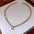 Dettaglio della collana di perle marroni con ciondolo a fiore argento e catena - Perline marroni con ciondolo a fiore in metallo (WN1907)