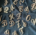 Elegant rose gold alphabet brooches with white crystals on a navy blue fabric - Rose Gold A
