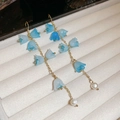 Détail de boucles d'oreilles muguet avec pétales bleus, chaînes dorées et perles - Crochet d'oreille - Or / Bleu