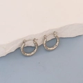 Close-up of silver oval hoop earrings with irregular geometric textured surface - Silver Geometric Faceted Hoop