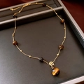 Detail of vintage gold bead chain with round tiger eye stones on jewelry tray - 35# Gold-Coffee