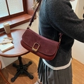Retro burgundy underarm bag featuring suede patchwork and a gold buckle on a cafe table - Red