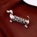 Detailed macro shot of a silver dachshund brooch with tricolor rope wrap on red silk - Brooch / Silver