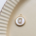 Detail of a 18k gold plated round shell pendant featuring a zircon encrusted letter G - G Round