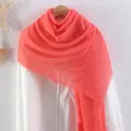 Solid coral red crinkled linen scarf with fringed edges draped on a white shirt - Coral