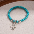 Dettaglio macro del bracciale di perle boho con perline turchesi e pendente a croce d'argento - Piccolo / Blu