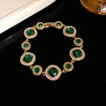 Pulsera vintage de oro con piedras esmeralda y detalles de diamantes sobre fondo negro - Oro-Verde