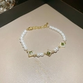Macro shot of green square zircon accents and white pearls on a vintage gold bracelet - Pearl Square Green Stone Style