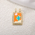 Macro view of a gold tarot pendant featuring cactus enamel inlay and zircon borders - Orange Enamel Cactus
