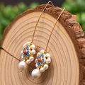 Primer plano detallado de pendientes vintage de flores de esmalte y perlas en madera - Gancho de Perla de Cloisonné