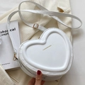 Detail of white heart-shaped bag with gold hardware on a cream blazer background - White